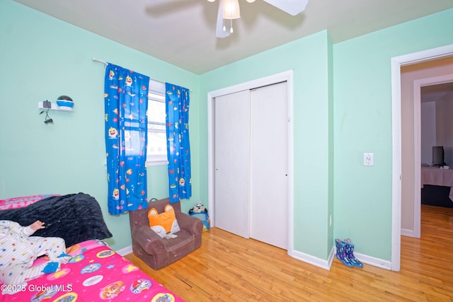bedroom featuring baseboards, ceiling fan, a closet, and wood finished floors
