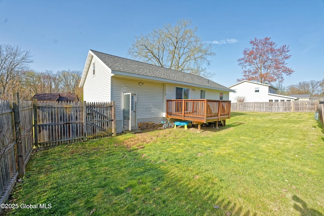 back of house featuring a fenced backyard, roof with shingles, a lawn, and a deck
