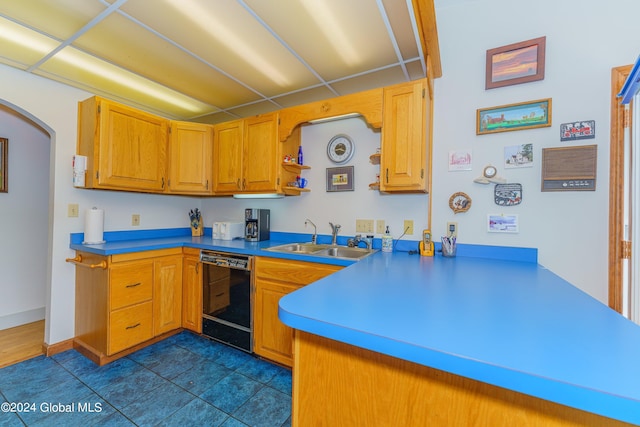kitchen with dark tile patterned flooring, a sink, arched walkways, dishwasher, and a peninsula