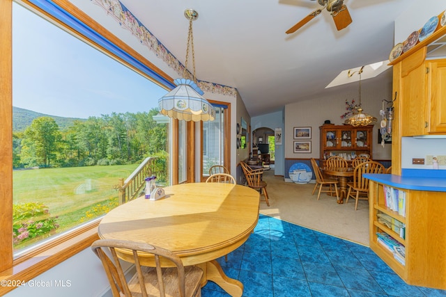 dining room with arched walkways, lofted ceiling, ceiling fan, and dark carpet
