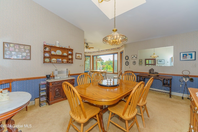 dining area featuring wallpapered walls, light carpet, and ceiling fan with notable chandelier