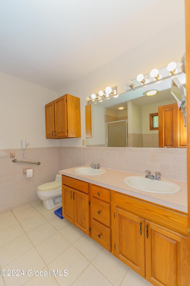 bathroom with tile patterned floors, a sink, a stall shower, and wainscoting