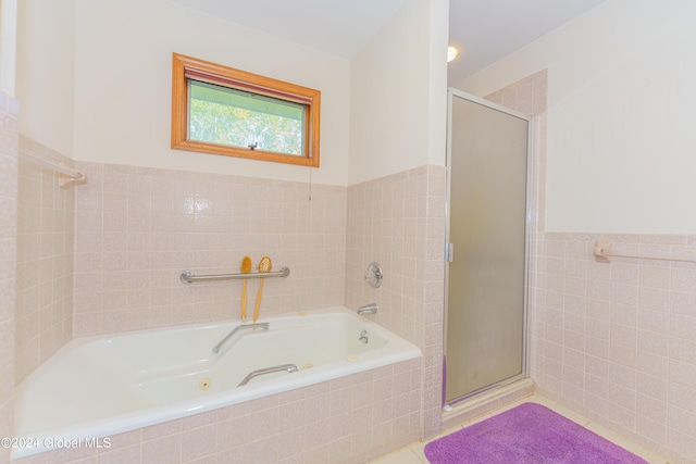 full bathroom with a stall shower, a jetted tub, tile patterned flooring, and tile walls