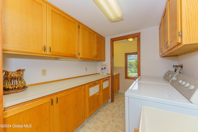 laundry room featuring washing machine and clothes dryer, cabinet space, tile walls, and wainscoting