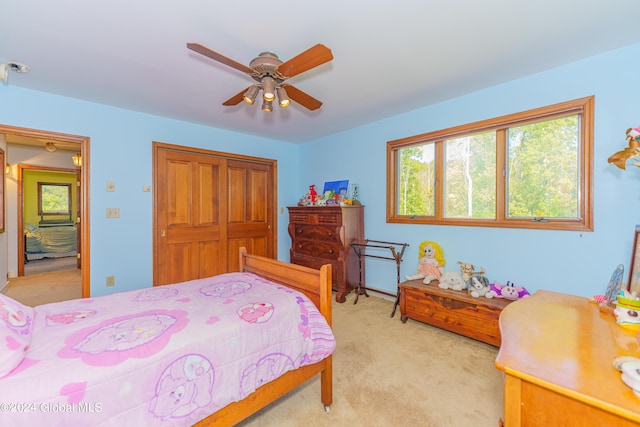 bedroom with light colored carpet, a closet, and a ceiling fan