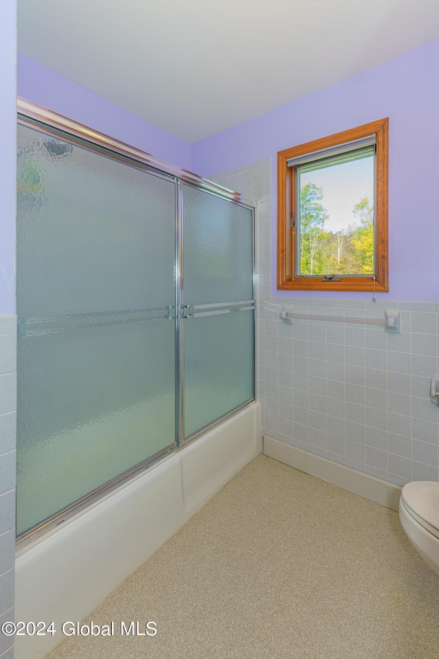 full bath featuring a wainscoted wall, tile walls, toilet, enclosed tub / shower combo, and carpet