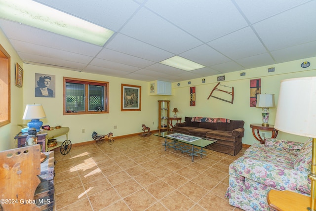 living area with a drop ceiling, light tile patterned floors, and baseboards