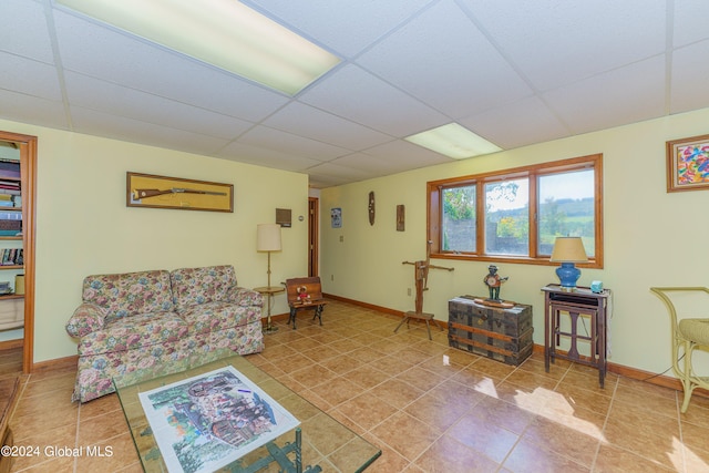 living room with baseboards, tile patterned flooring, and a paneled ceiling