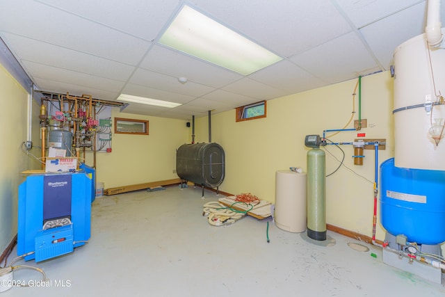 finished below grade area with a heating unit, baseboards, heating fuel, and a paneled ceiling