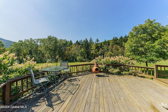wooden deck with outdoor dining area and a view of trees
