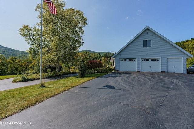 view of side of home with a yard, a garage, and a mountain view