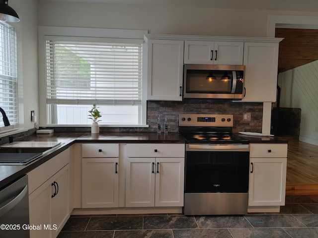 6 Father Jogues Pl, Ticonderoga, NY 12883 - kitchen with appliances with stainless steel finishes, a sink, dark countertops, dark stone finish flooring, and white cabinets