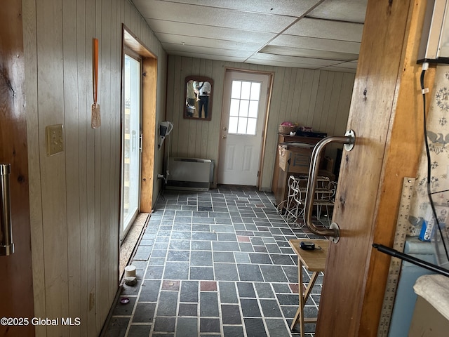 doorway to outside with wood walls and brick patterned floors