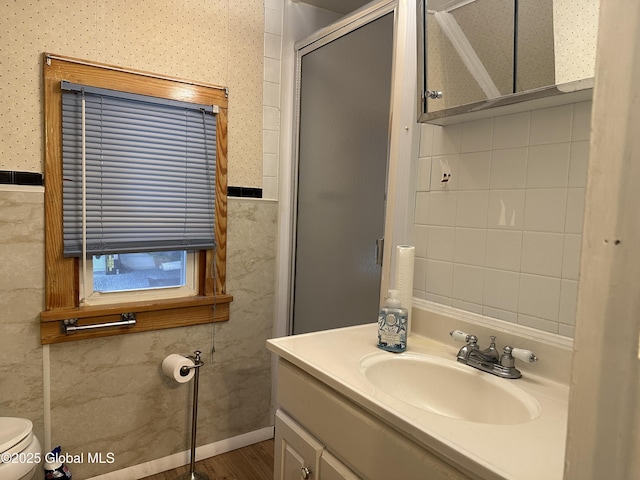 full bath with a stall shower, vanity, toilet, tile walls, and wood finished floors