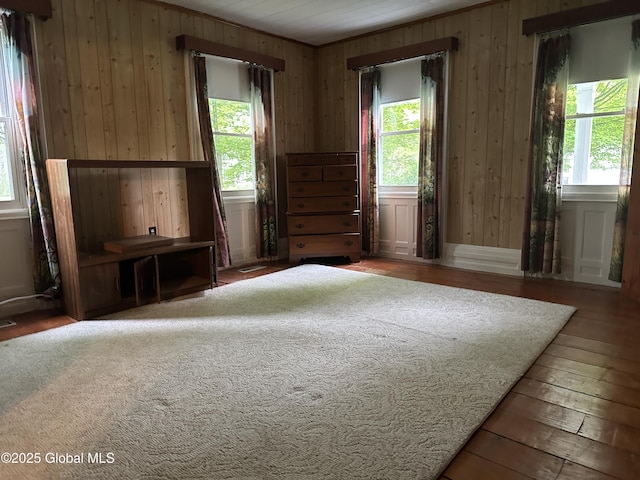 unfurnished room with healthy amount of natural light, hardwood / wood-style flooring, and wood walls