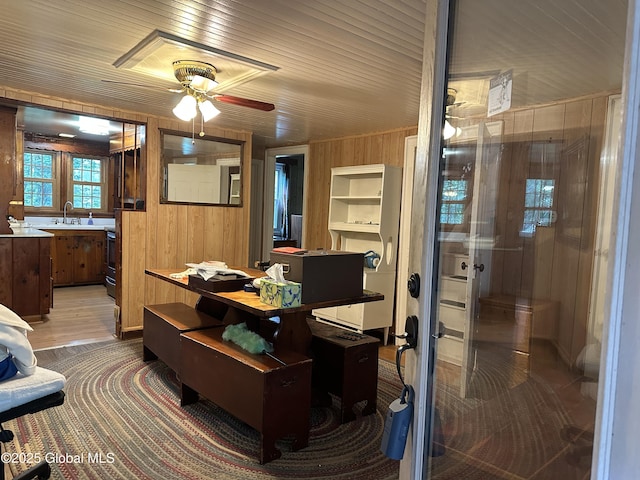 office space with wood walls, ceiling fan, a sink, and carpet