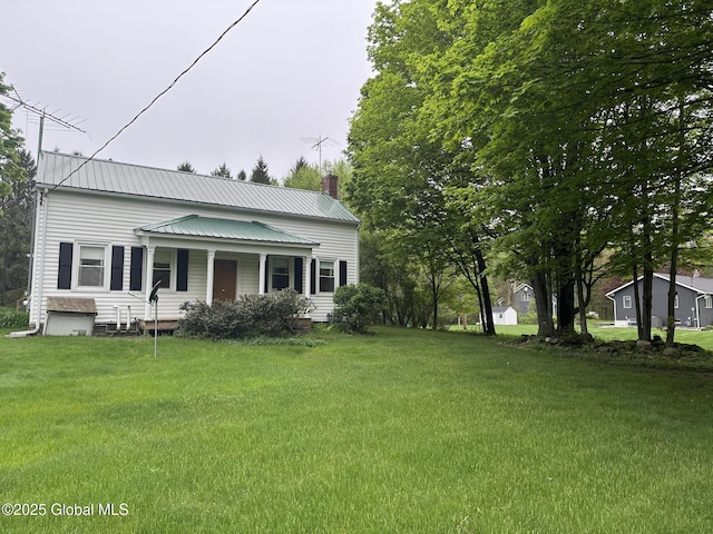 view of front of property featuring a chimney, a front yard, metal roof, and a porch