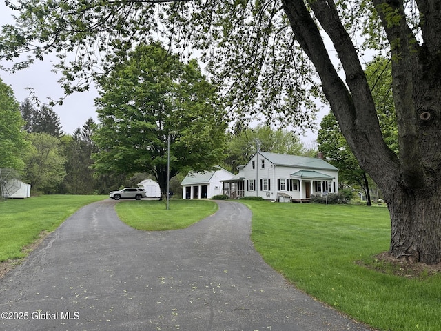 view of front facade featuring asphalt driveway, a front lawn, and a chimney