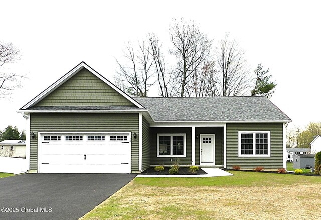 ranch-style home featuring a garage, aphalt driveway, and a front lawn