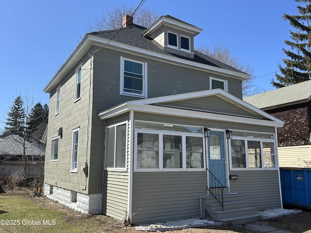 traditional style home featuring a chimney, roof with shingles, and entry steps