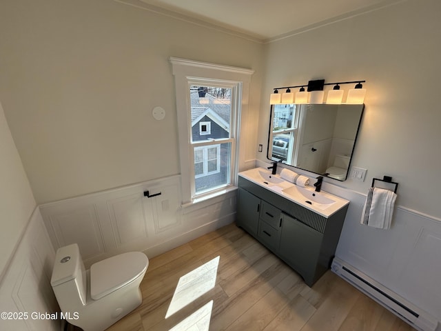 bathroom with toilet, wood finished floors, wainscoting, and a baseboard radiator