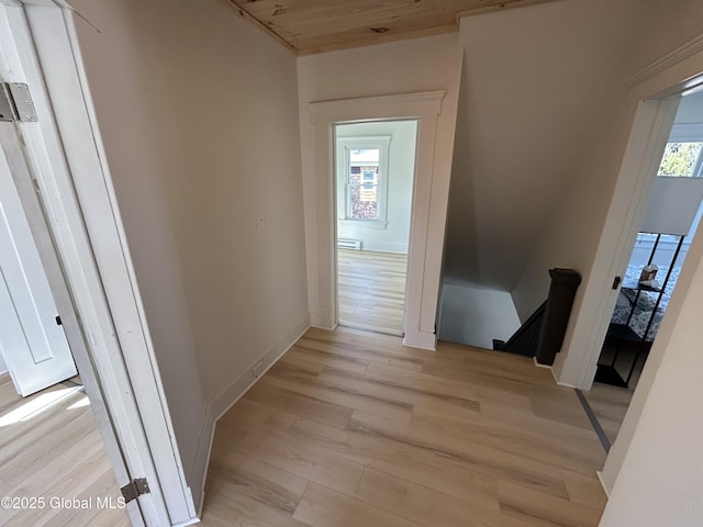 corridor featuring baseboards, an upstairs landing, and light wood-style floors