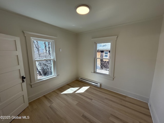 empty room with baseboards, light wood-style flooring, a baseboard heating unit, and ornamental molding