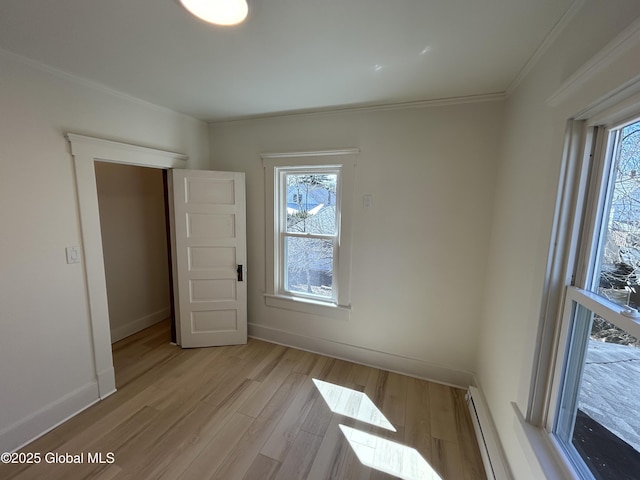 unfurnished room with baseboards, ornamental molding, and light wood-style flooring
