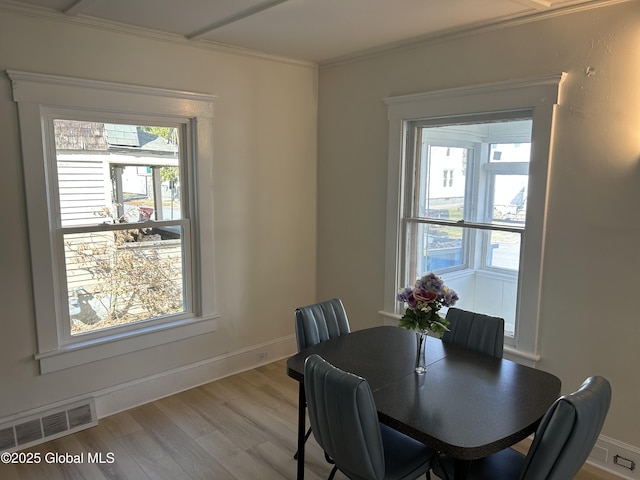 dining room with baseboards, light wood-style flooring, visible vents, and crown molding