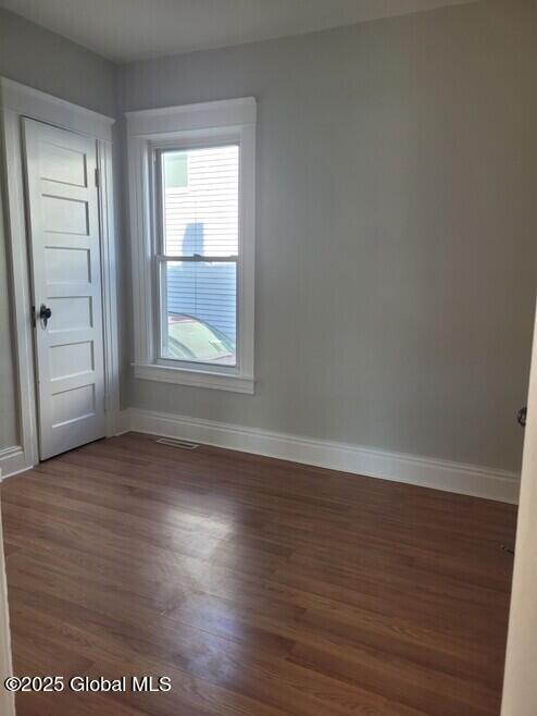 unfurnished room with wood finished floors, baseboards, and visible vents