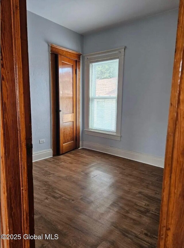 empty room featuring dark wood-type flooring and baseboards