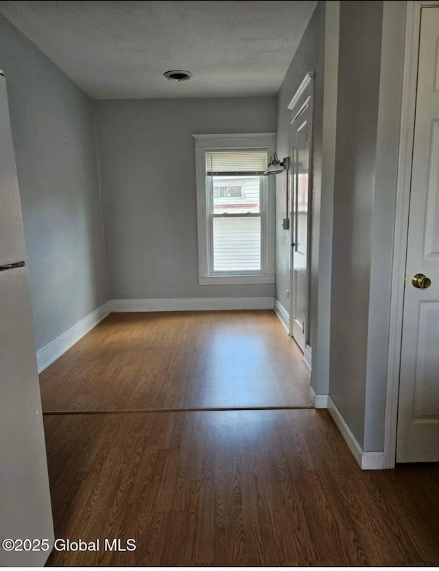 empty room featuring visible vents, baseboards, and wood finished floors