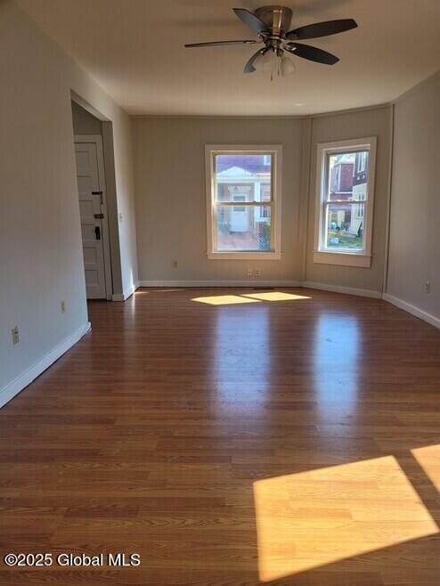 empty room featuring wood finished floors, ceiling fan, and baseboards