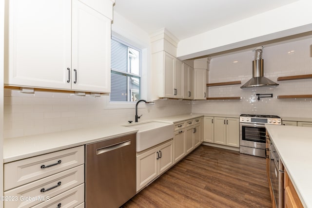 kitchen with wall chimney range hood, dark wood-style floors, open shelves, stainless steel appliances, and a sink