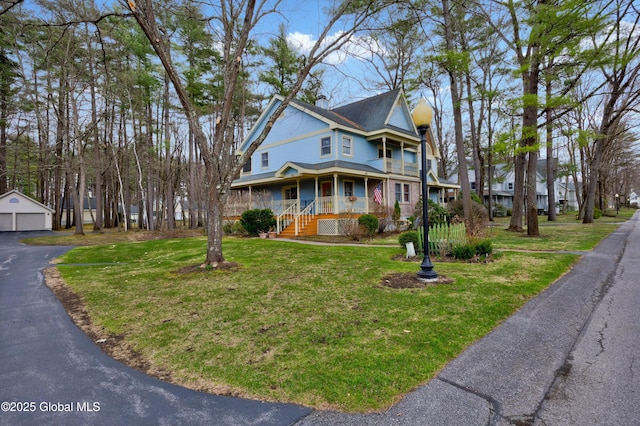 victorian home with a chimney, an outdoor structure, covered porch, a detached garage, and a front yard