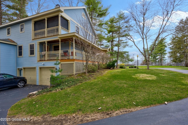view of side of home featuring a chimney, aphalt driveway, a yard, and a garage