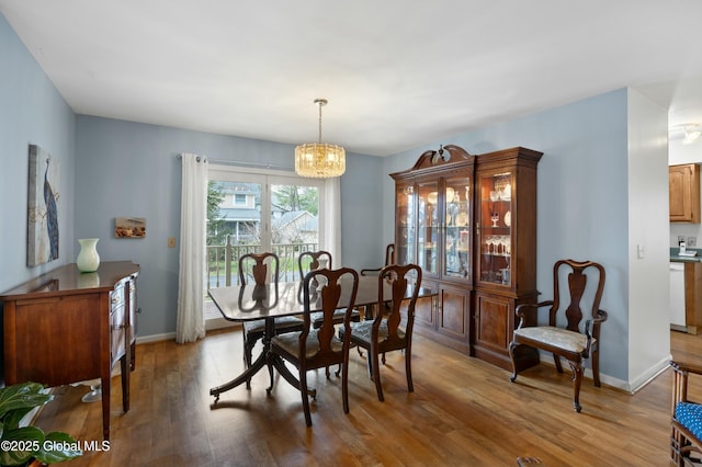 dining area featuring baseboards, a notable chandelier, and wood finished floors