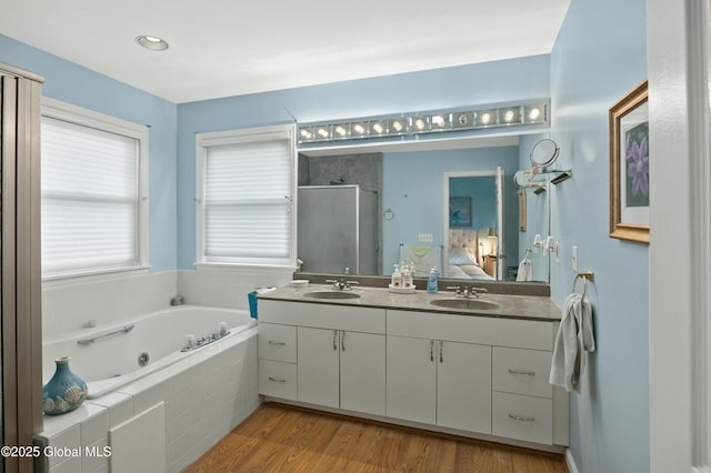 ensuite bathroom with a whirlpool tub, a sink, double vanity, and a stall shower