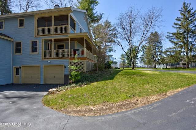 view of front facade with an attached garage, driveway, a chimney, and a front lawn