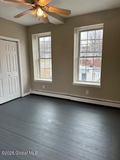 unfurnished bedroom featuring a closet, dark wood-style flooring, a baseboard radiator, and ceiling fan