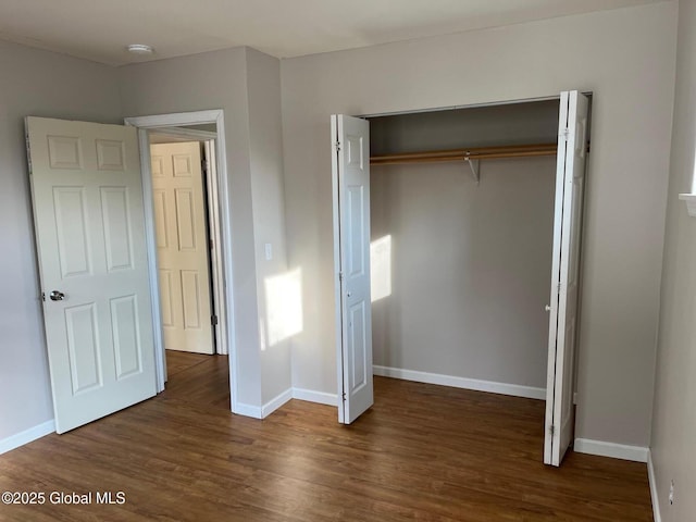 unfurnished bedroom with a closet, baseboards, and wood finished floors