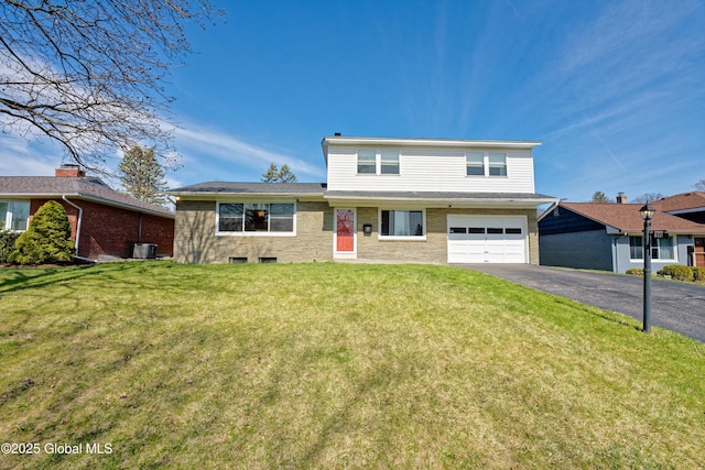traditional-style home featuring an attached garage, a front yard, and aphalt driveway