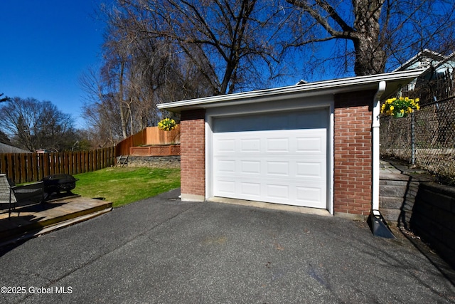 garage featuring aphalt driveway and fence