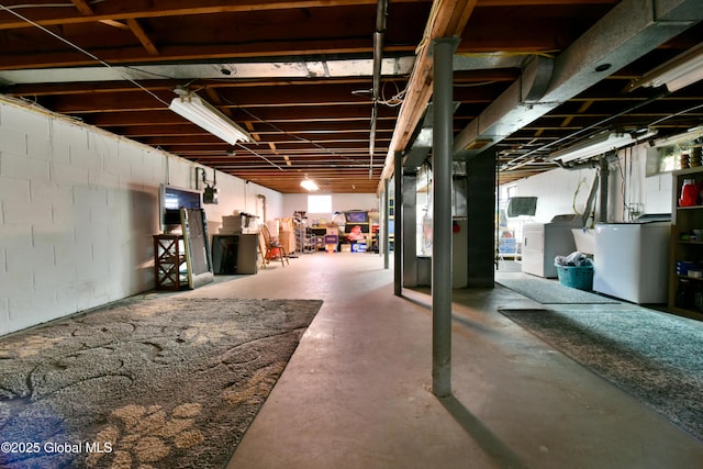 unfinished below grade area featuring concrete block wall, separate washer and dryer, and fridge