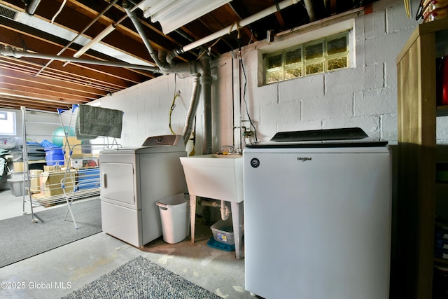 laundry room with concrete block wall, laundry area, and washer and clothes dryer