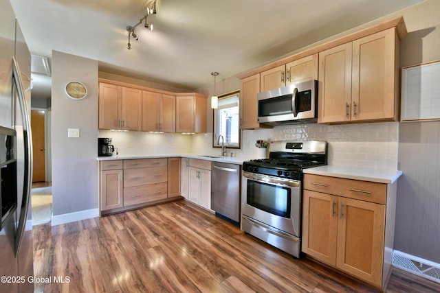 kitchen featuring light countertops, light brown cabinets, stainless steel appliances, and wood finished floors