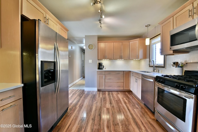 kitchen with light brown cabinetry, appliances with stainless steel finishes, a sink, and light countertops