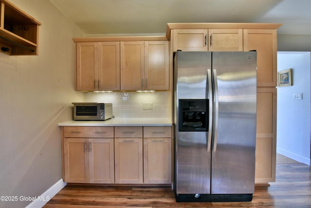 kitchen featuring light brown cabinetry, stainless steel fridge with ice dispenser, baseboards, a toaster, and backsplash