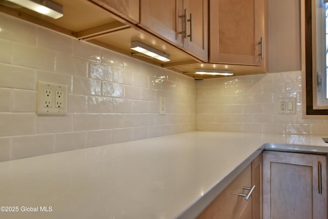 room details featuring light countertops, brown cabinets, and tasteful backsplash