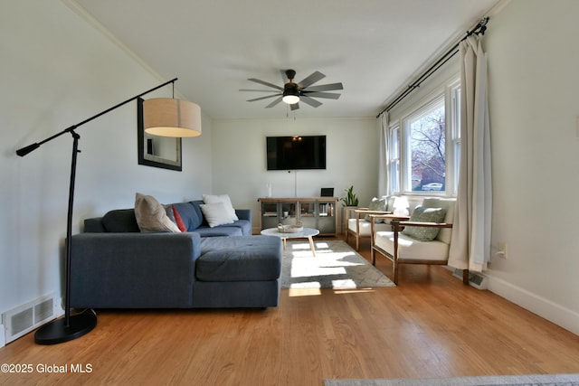 living room with a ceiling fan, visible vents, and wood finished floors